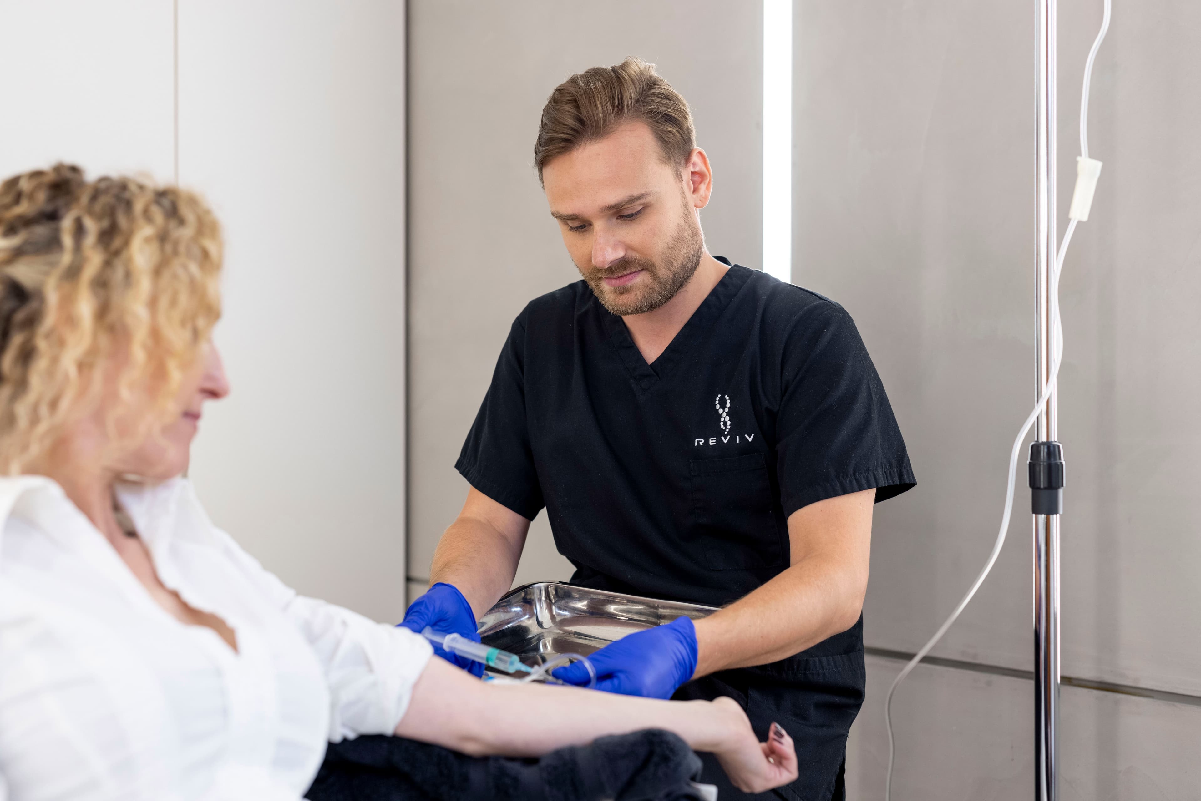 REVIV nurse administering an IV drip to a female client in a professional clinic setting